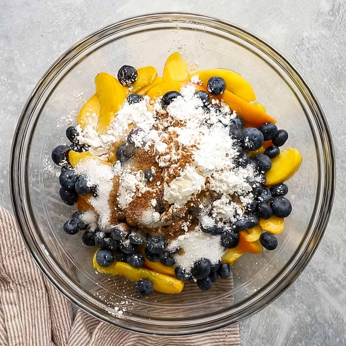 peach, blueberries, and rest of the fruit filling ingredients in a bowl.