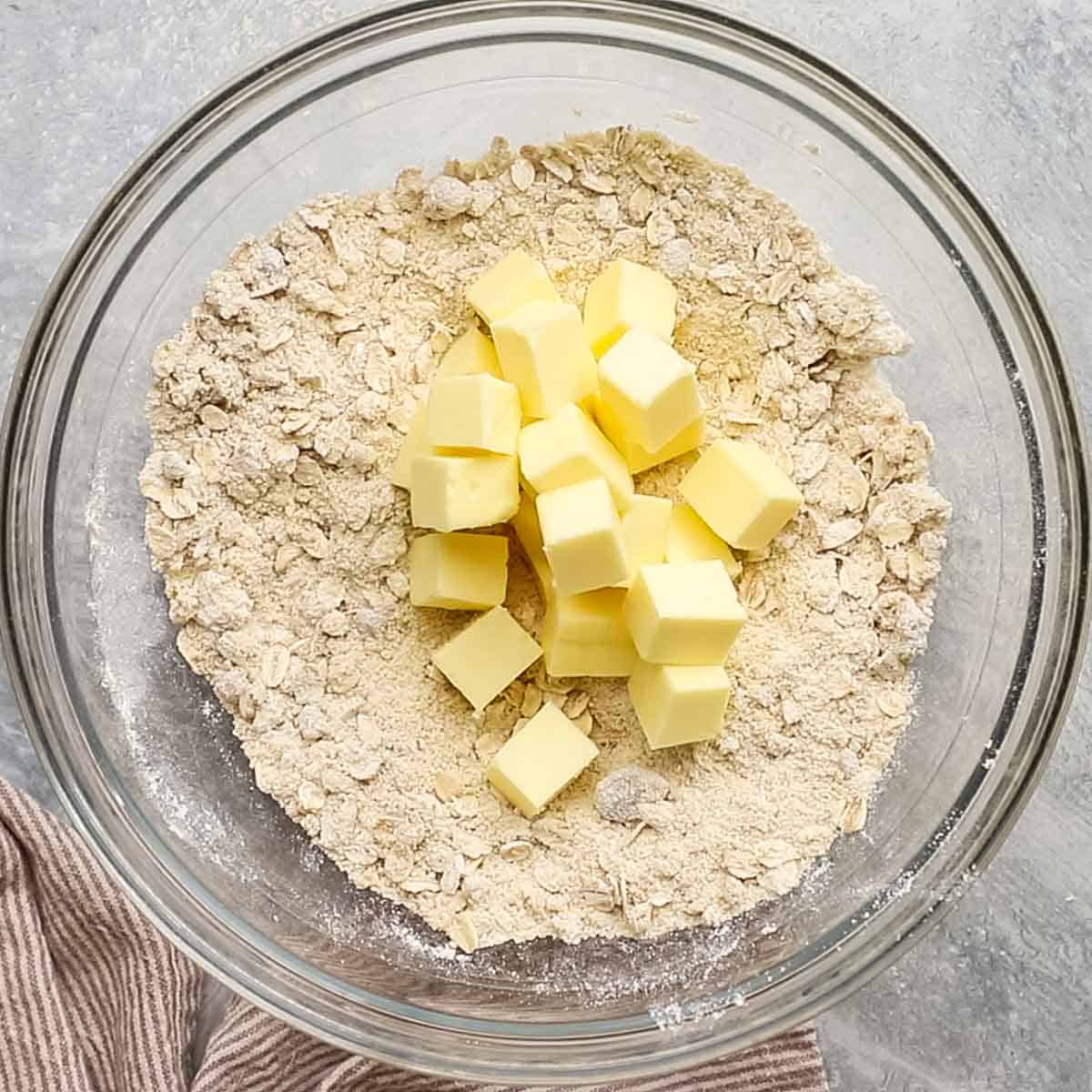 cubed butter added to the bowl with flour and oats mixture