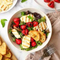 mixed greens topped with fresh strawberries and grilled halloumi