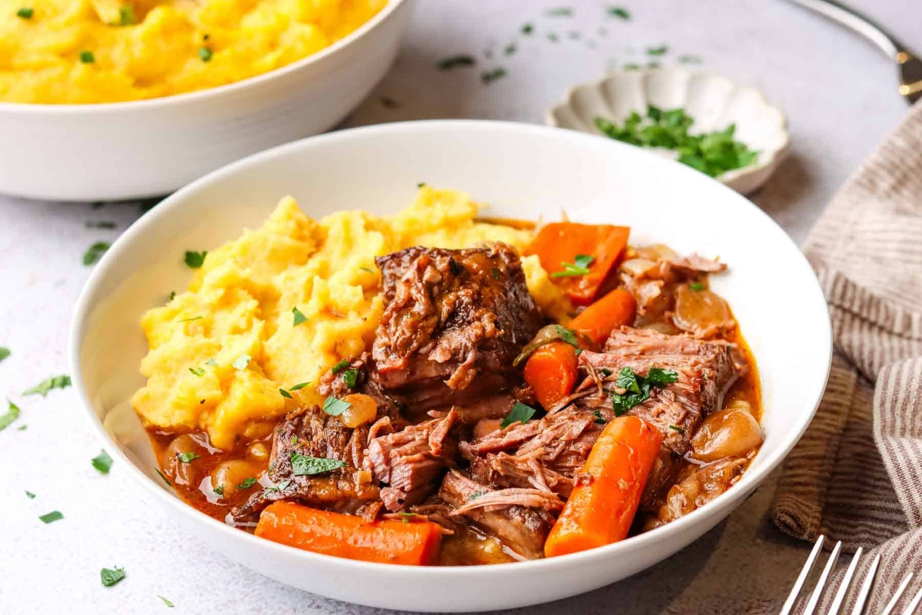 a plate of mashed potatoes, braised beef and veggies