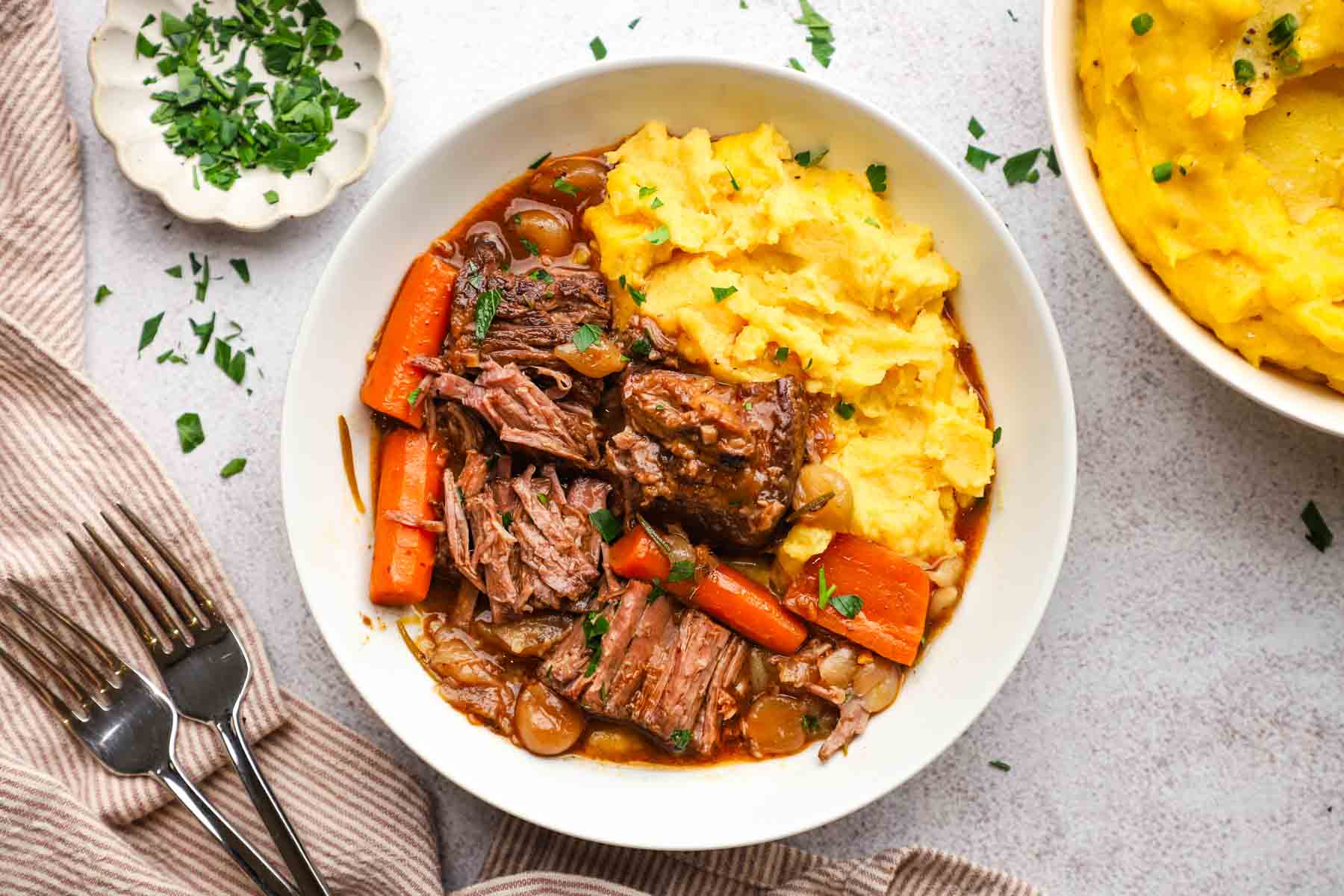 overhead view of a serving plate with braised beef and mashed potatoes.