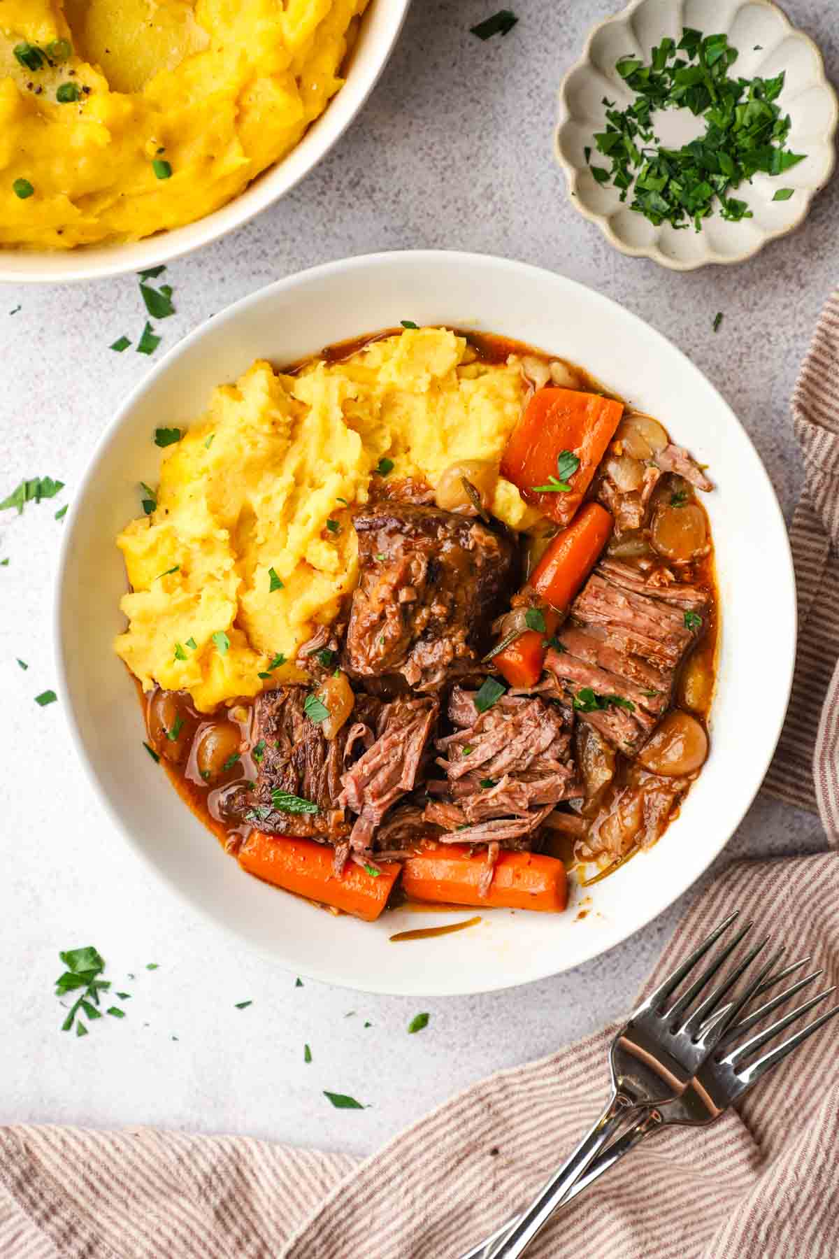 overhead view of a serving plate with braised beef and mashed potatoes.