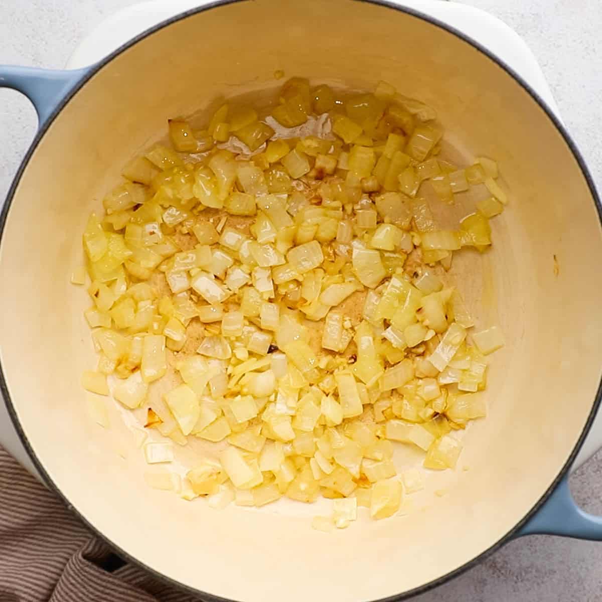 a dutch oven with onions and garlic  being cooked in some oil