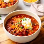 a bowl of sweet potato chili topped with shredded cheese and sour cream
