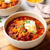 a bowl of sweet potato chili topped with shredded cheese and sour cream