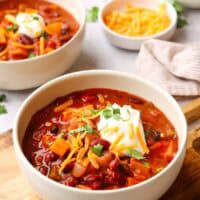 a bowl of sweet potato chili with sour cream, shredded cheese as toppings