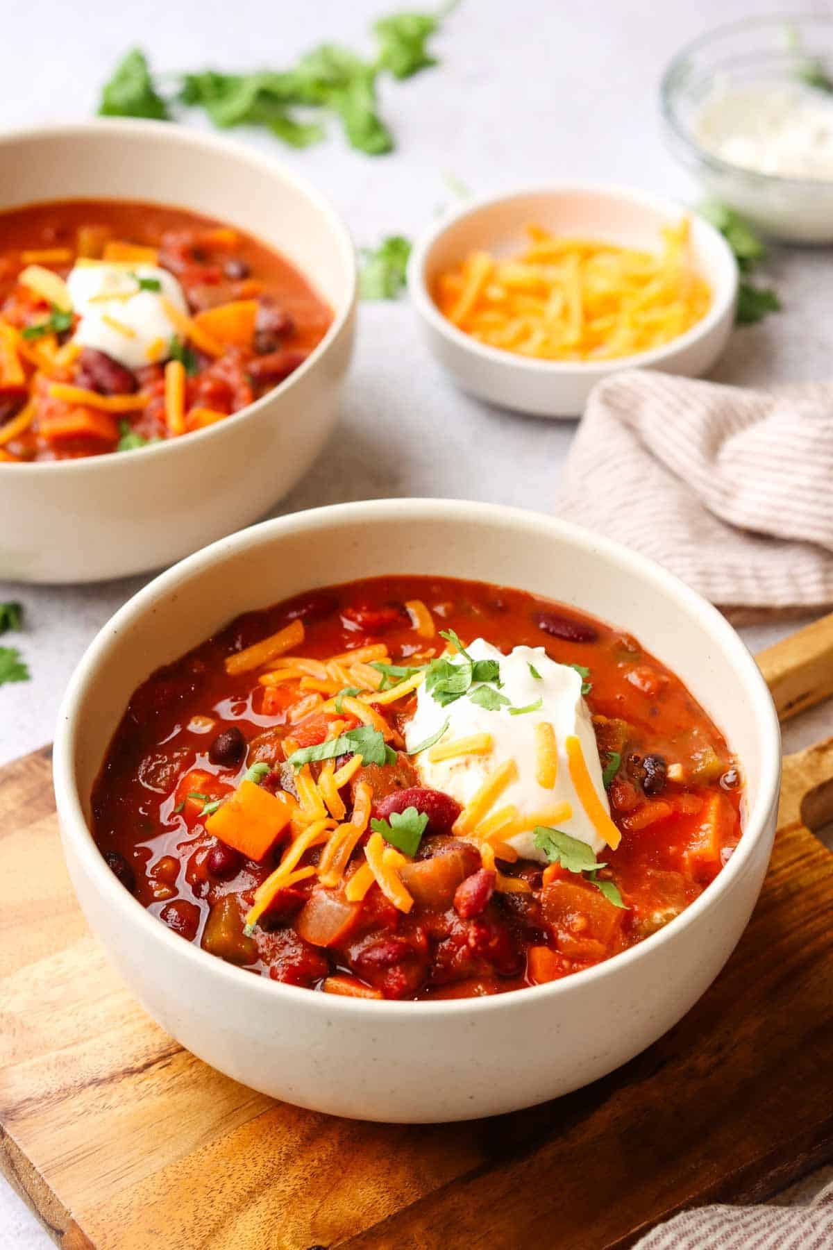 a bowl of sweet potato chili with sour cream, shredded cheese as toppings