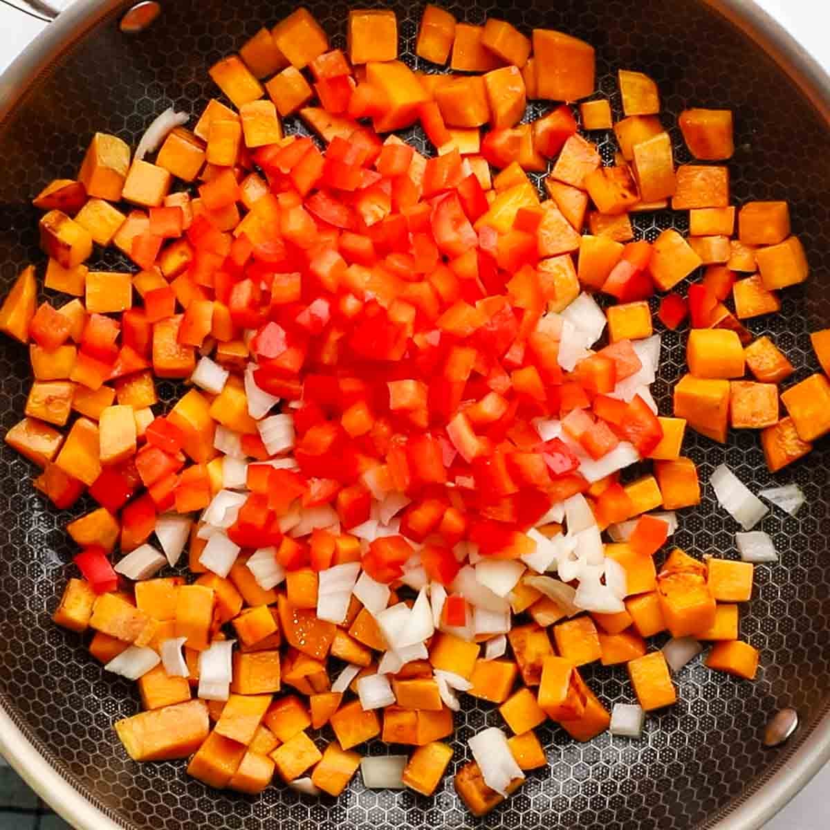 diced onion and bell pepper added to the skillet with sweet potatoes