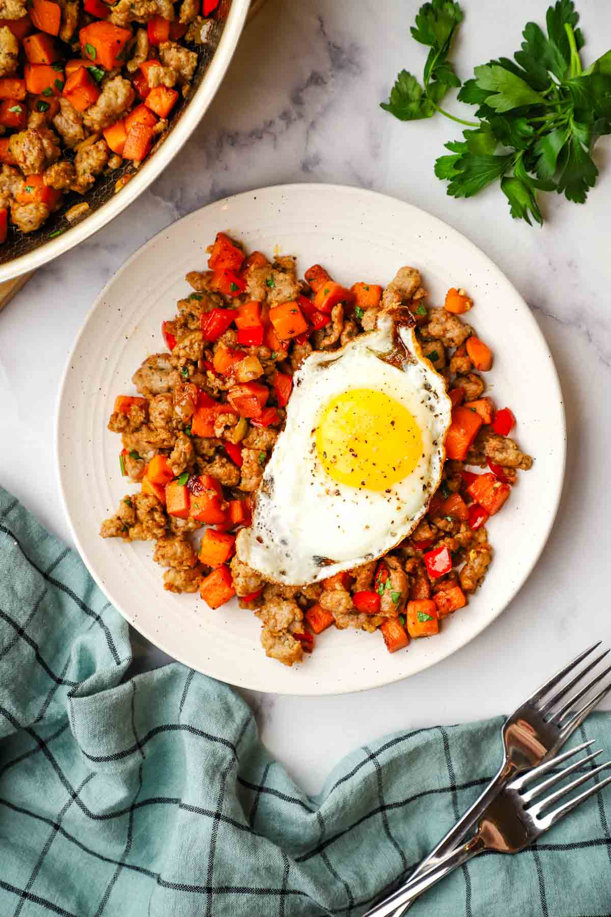 overhead view of a plate of sweet potato and sausage hash served with a fried egg on top